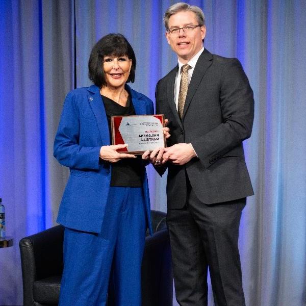 Crain's Executive Editor Mickey Ciokajlo poses while presenting GVSU 菲洛梅娜五世总统. Mantella with a Newsmaker of the Year plaque.